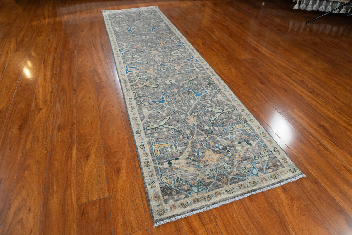 Farahan Afghan traditional runner with charcoal floral field and beige border, angled view on a wood floor