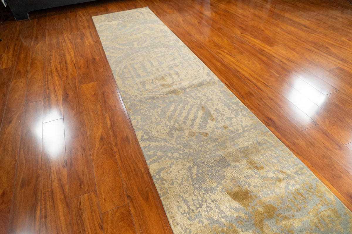 Nummus Nepali modern runner with gold and gray abstract pattern, angled view on a wood floor