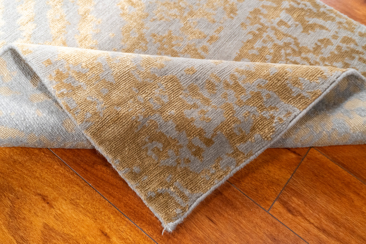 Folded corner of the Nummus Nepali runner showing the back with gold and gray pattern